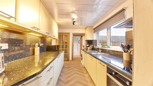 A modern kitchen with granite countertops, stainless steel appliances, and a large window providing natural light. - Host Stay Inness House (Bedlington)