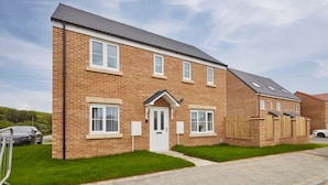 A two-story brick house with a white door, windows, and a small front yard. - Host Stay Cayton Bay Cottage (Scarborough)