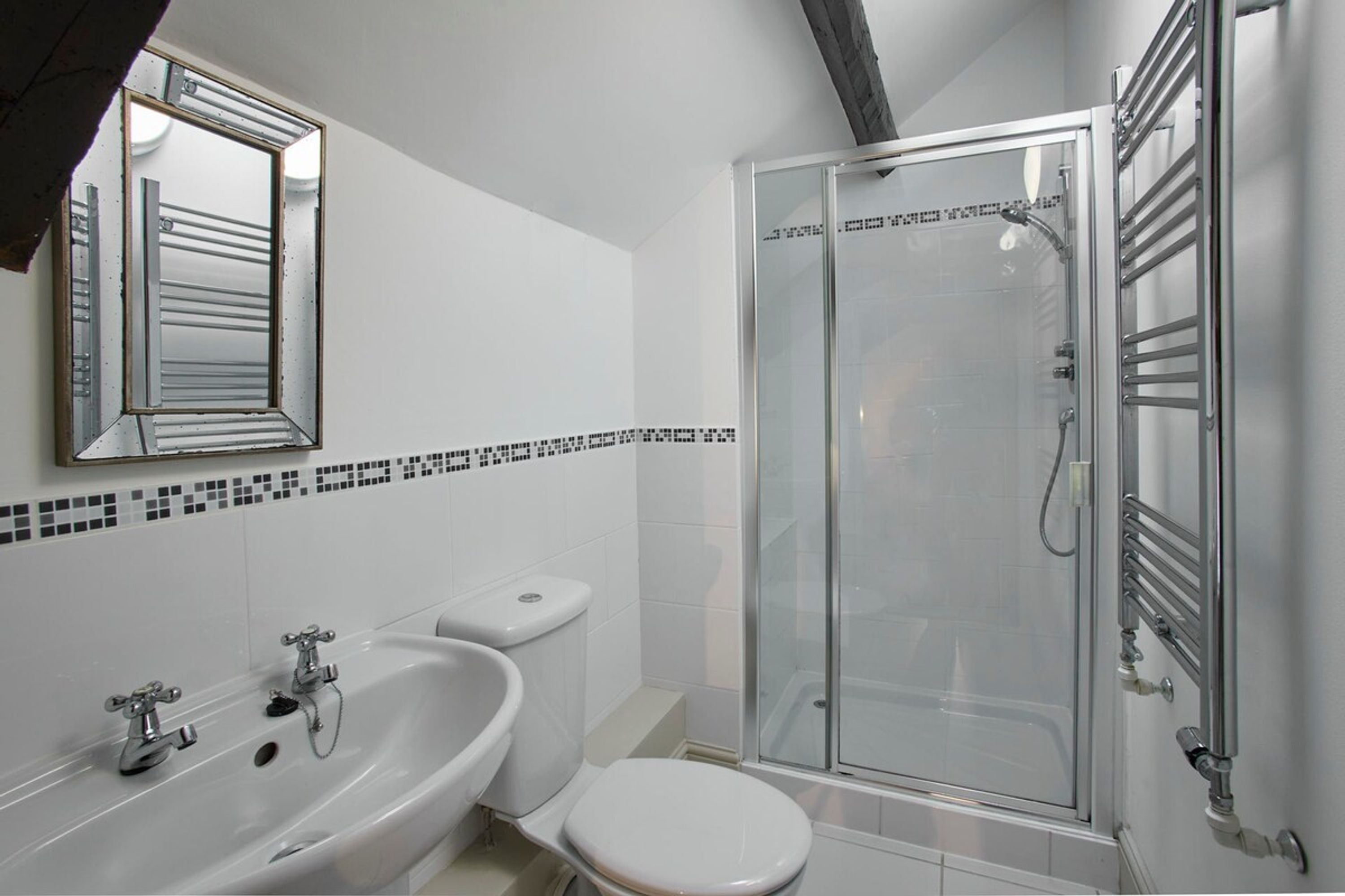 A bathroom with a glass shower enclosure, a white sink, and a toilet.
