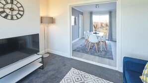 Un salon moderne avec un téléviseur à écran plat, un tapis à motifs et un canapé bleu.