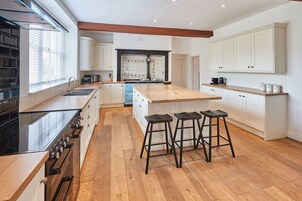 A modern kitchen with a central island, bar stools, and a built-in oven.
