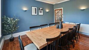 A dining room with a wooden table and chairs, blue walls, and wall-mounted lights. - Host Stay Silton Hall (Thirsk)