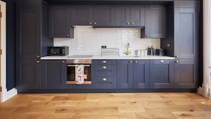 A modern kitchen with dark cabinetry, a white countertop, and a wooden floor.