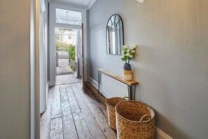 A hallway with a wooden floor, a radiator, a bench, and two wicker baskets. - Host Stay Hidden Gem (Saltburn-by-the-Sea)