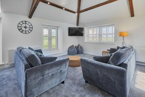A modern living room with grey sofas, a flat-screen TV, and a large window with a view of the outdoors. - Host Stay 1 The Mount (Whitby)