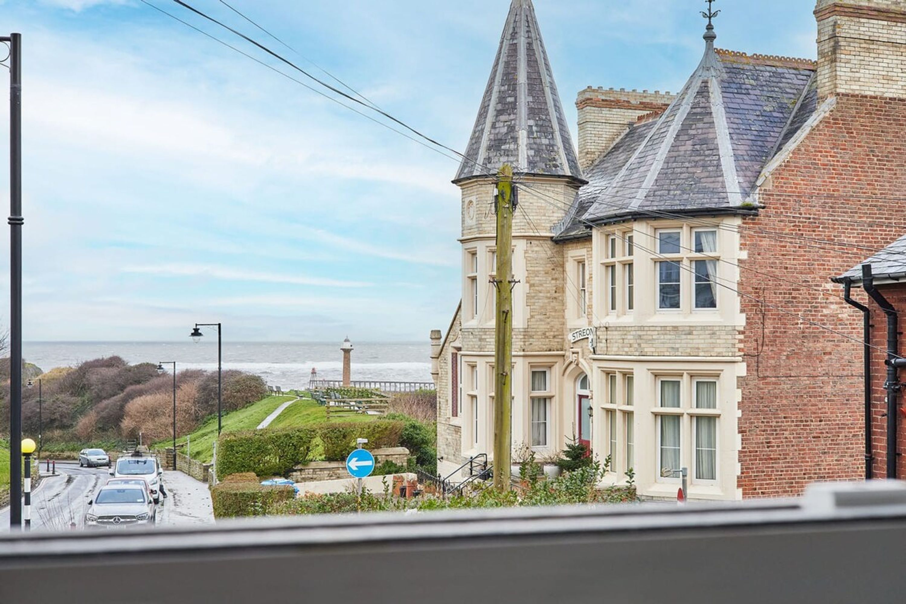 A coastal building with a prominent tower, a view of the sea, and a sign reading "STREON".
