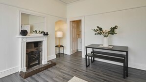 A room with a fireplace, a table with a vase, and a lamp. - Host Stay Scoresby Place (Whitby)