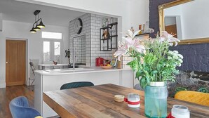 A dining area with a wooden table, yellow and blue chairs, and a vase of flowers. - Host Stay Upleatham Street (Saltburn-by-the-Sea)