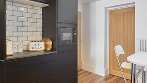 A modern kitchen with black cabinetry, a microwave, and a toaster on the countertop. - Host Stay Upleatham Street (Saltburn-by-the-Sea)