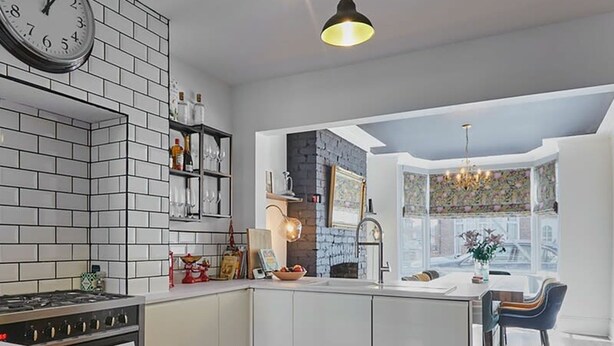 A modern kitchen with white cabinetry, a built-in island, a gas stove, and a wooden floor. - Host Stay Upleatham Street (Saltburn-by-the-Sea)