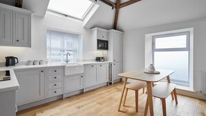 A modern kitchen with white cabinetry, a skylight, a microwave, and a dining area with a table and chairs. - Host Stay 3 The Mount (Whitby)