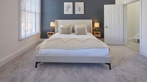 A bedroom with a bed, two bedside tables, a door, and a window with blinds. - Host Stay Castle View (Scarborough)