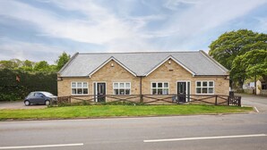 A stone building with a gabled roof, two doors, and a small porch. - Host Stay Britton Hall Bungalow (Bishop Auckland)
