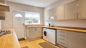 A modern kitchen with a stove, sink, and washing machine. - Host Stay Britton Hall Bungalow (Bishop Auckland)