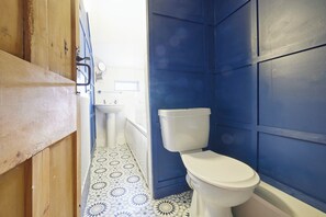 A bathroom with a white toilet, a sink, and a patterned floor.