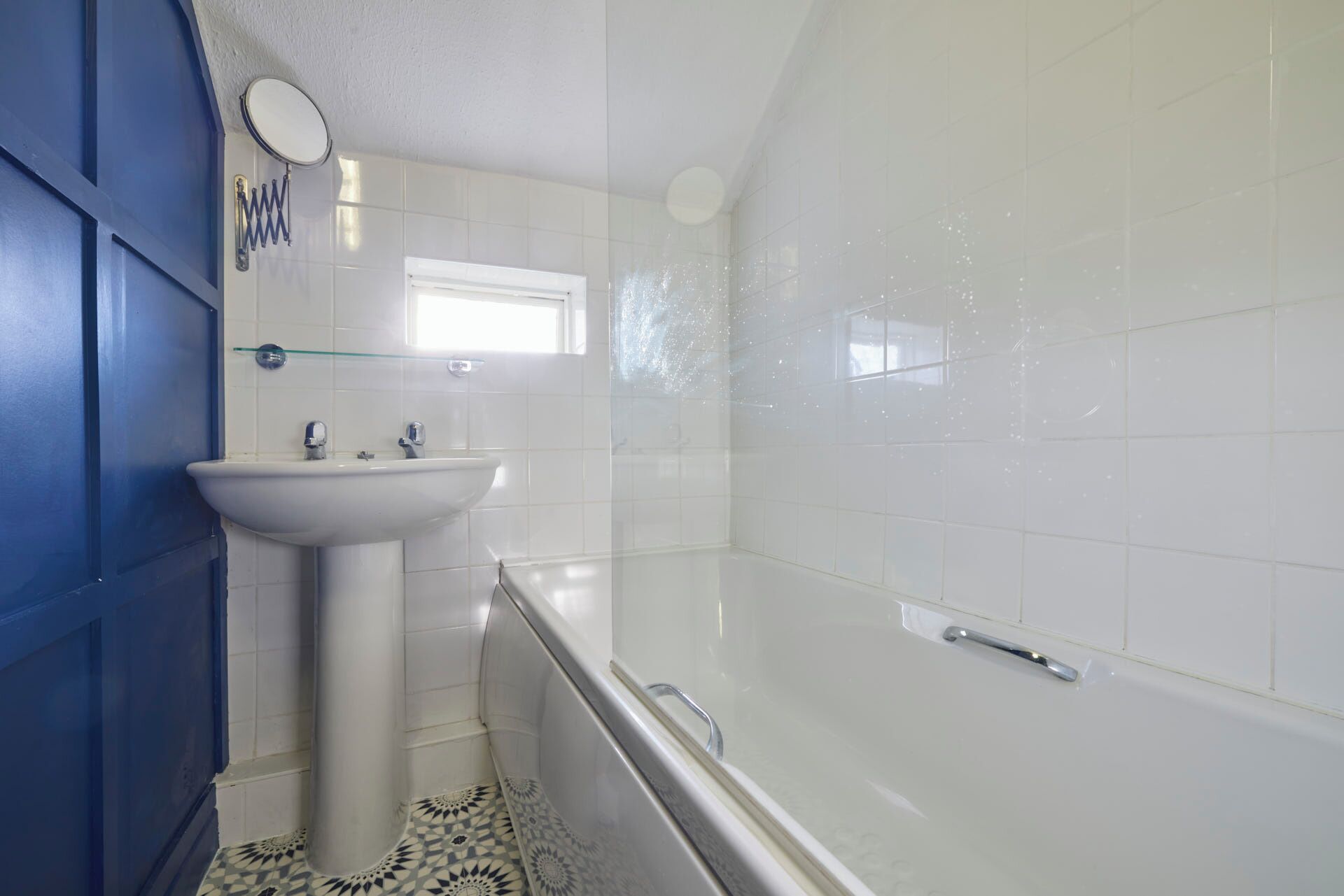 A bathroom with a white sink, a mirror, a window, and a bathtub.