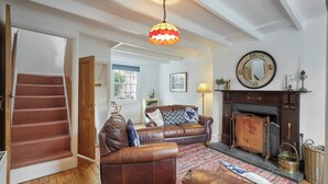 Una sala de estar con chimenea, sofá de cuero y una escalera.