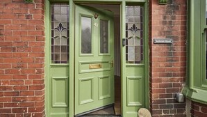 A green front door with a number plate, a 'Welcome' mat, and a 'Sunbeam House' sign. - Host Stay Sunbeam House (Saltburn-by-the-Sea)