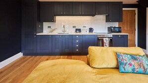 Una cocina pequeña con armarios oscuros, una encimera blanca y un microondas.
