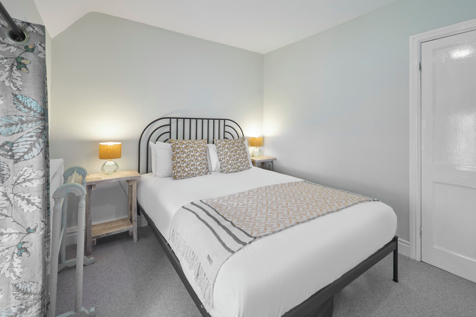 A neatly arranged bedroom with a bed, two bedside tables, and a nightstand.