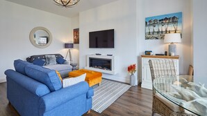 Ein modernes Wohnzimmer mit einem blauen Sofa, einem Glastisch und einem Kamin.