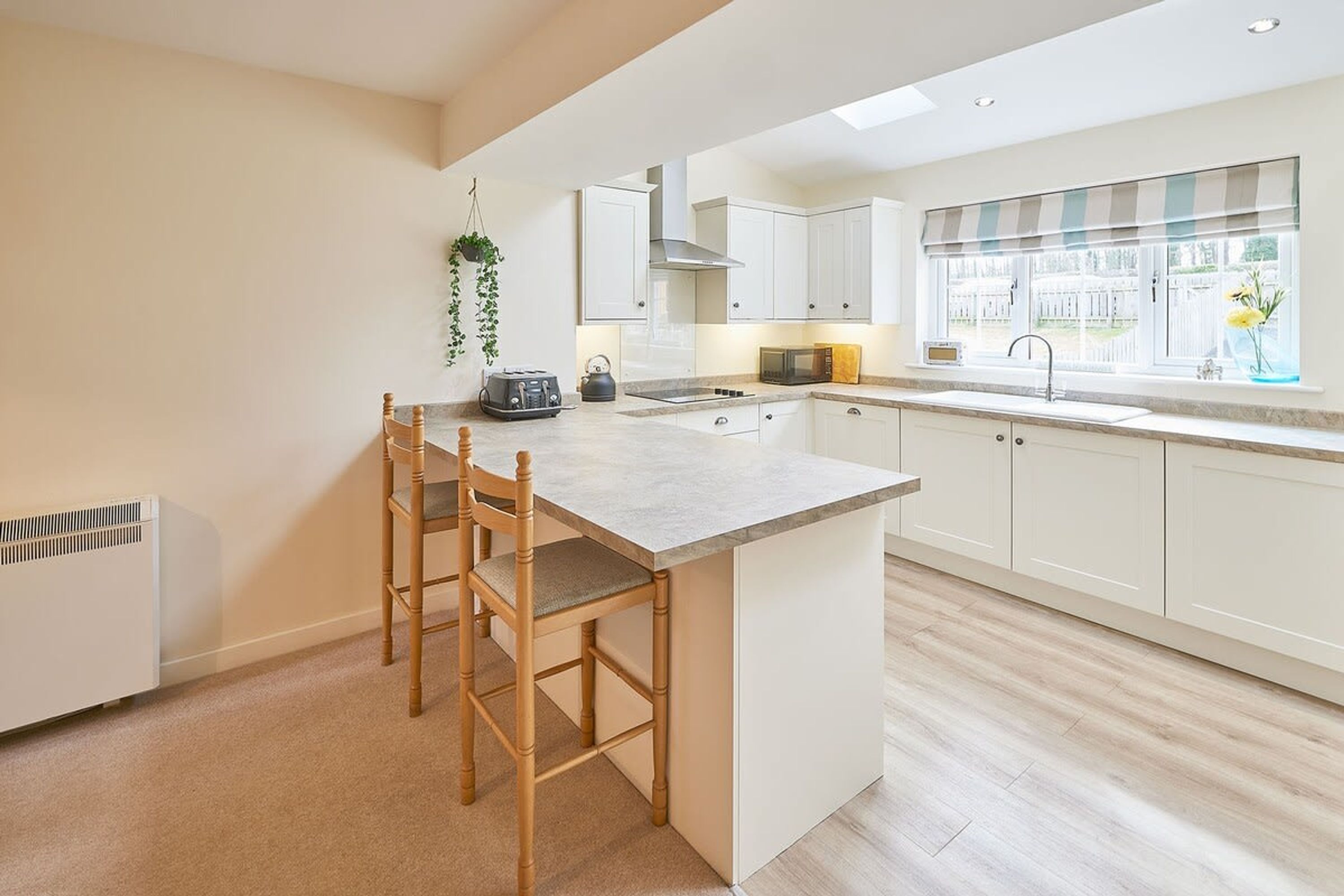 A modern kitchen with a central island, white cabinetry, and a window with a view.