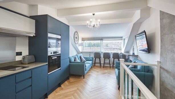 Une cuisine moderne dotée d’appareils électroménagers intégrés, un coin repas avec vue et un escalier avec des rampes en verre.