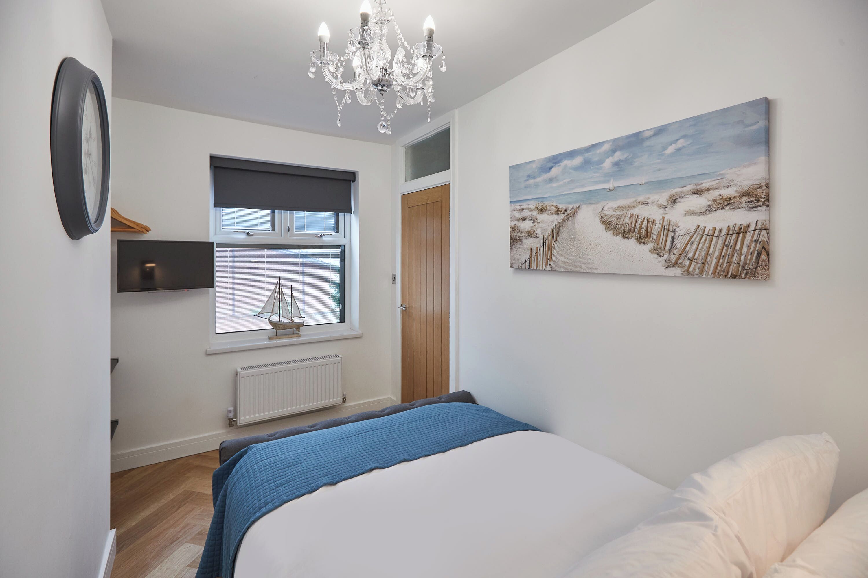Een slaapkamer met een bed, een raam met uitzicht, een schilderij en een kroonluchter.