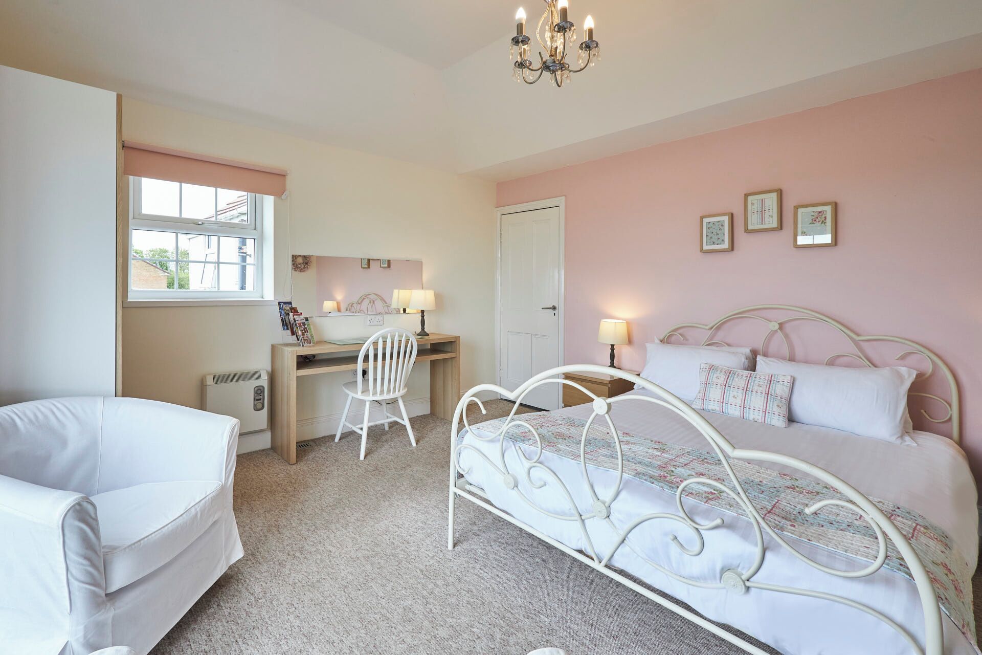 A bedroom with a bed, a desk, a chair, and a window.