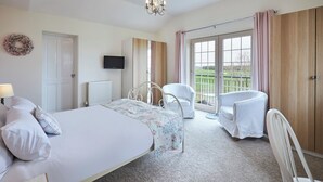 A bedroom with a bed, a chair, a TV, and a view through a large window. - Host Stay The Paddock (Bedlington)