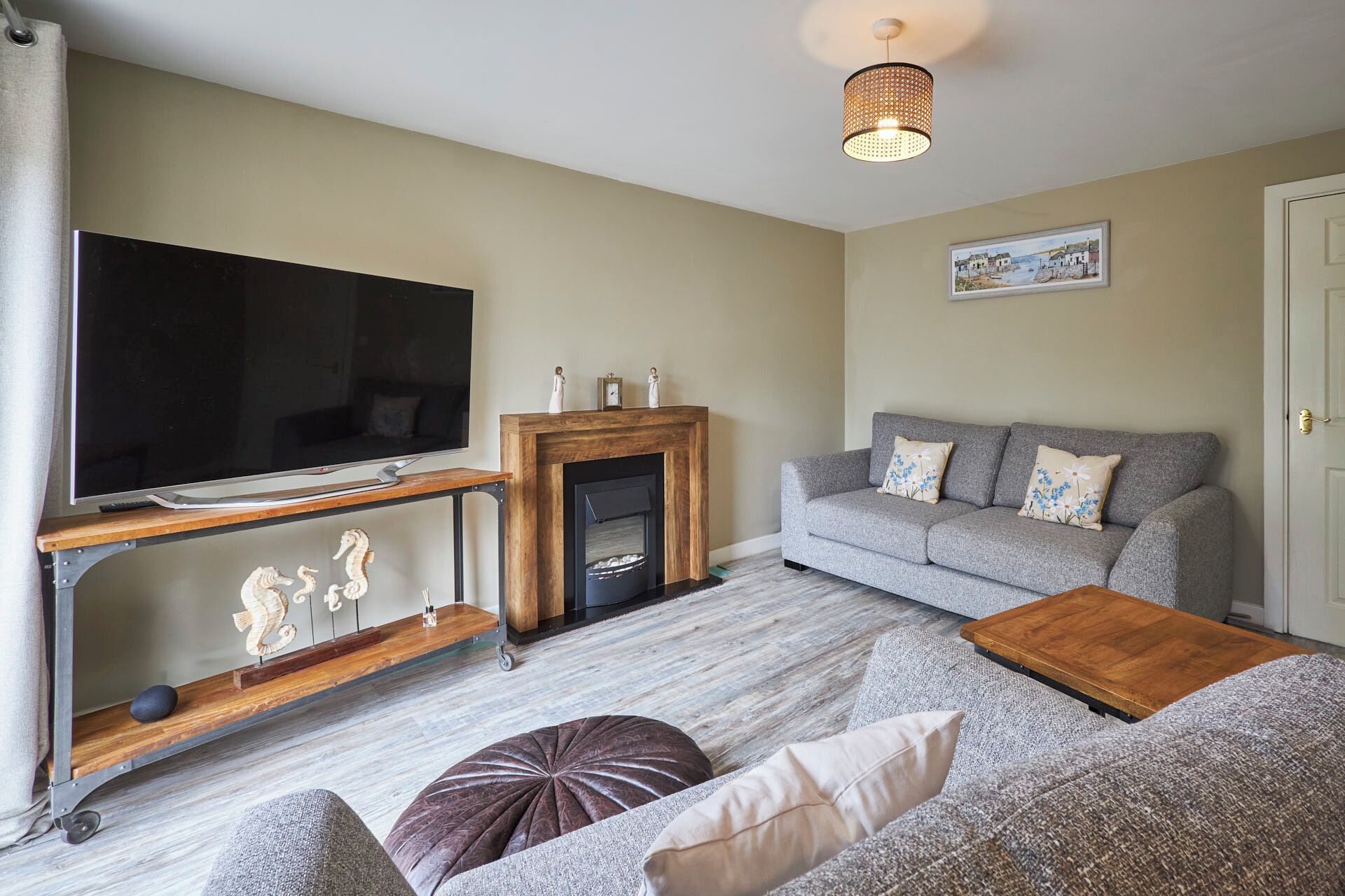 A living room with a flat-screen TV, a fireplace, a grey sofa, and a wooden coffee table.