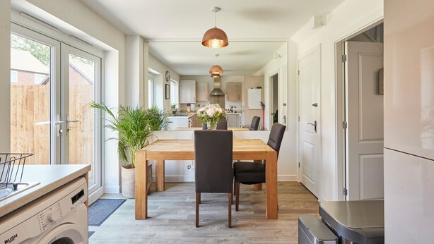 Una cocina moderna con comedor, suelo de madera y un ventanal grande.