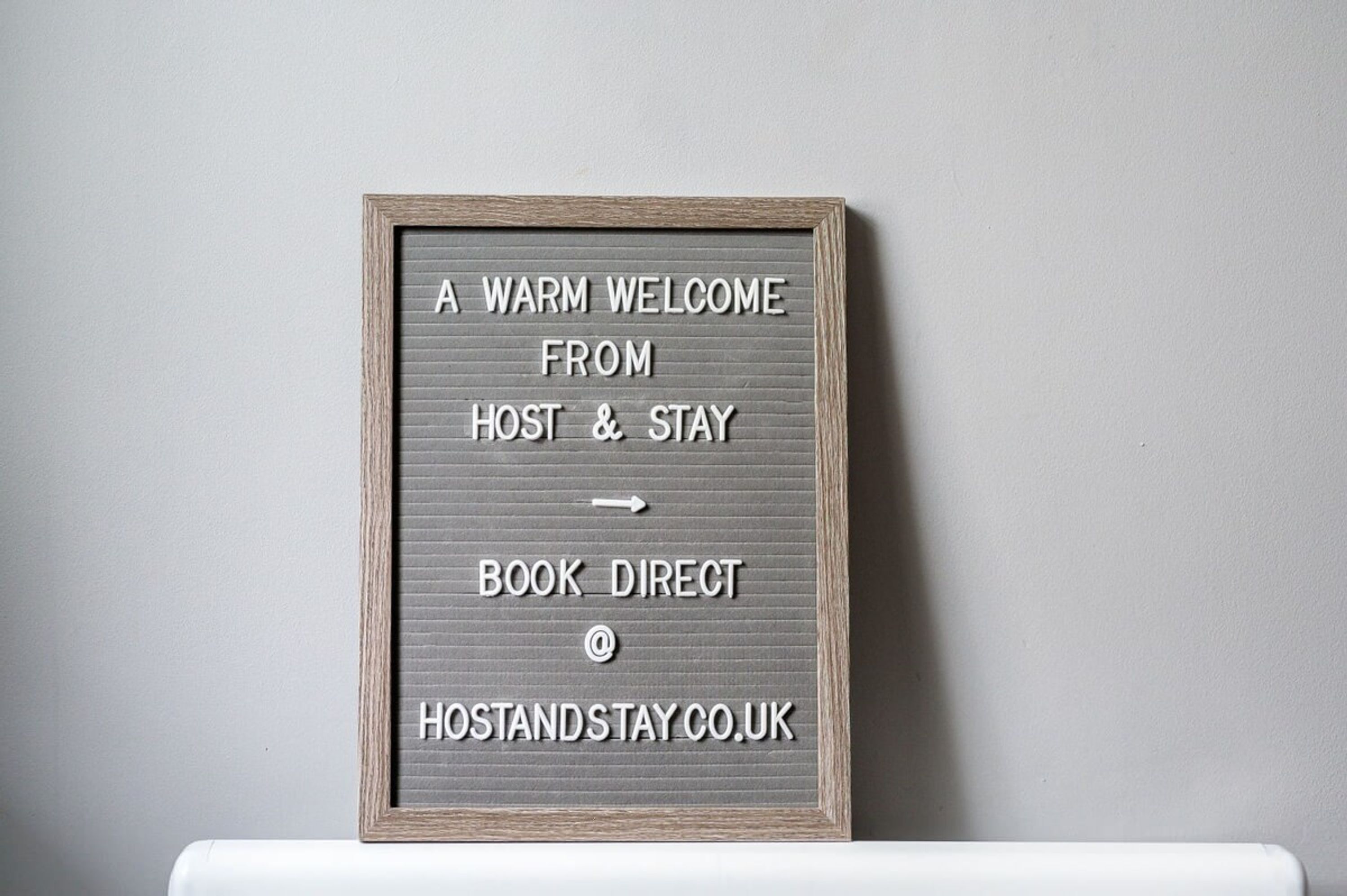 En ramme med et skilt, der opfordrer gæster til at booke direkte på HOSTANDSTAY.CO.UK.