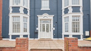 A two-story building with a white door and windows, a brick entrance, and a nameplate above the door. - Host Stay Northville Arrifana (Whitley Bay)