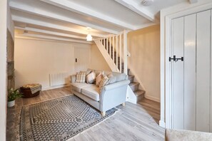 A living room with a sofa, a patterned rug, and a staircase. - Host Stay Daisy s Cottage (Hexham)