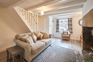 A living room with a sofa, a patterned rug, a fireplace, and a staircase. - Host Stay Daisy s Cottage (Hexham)