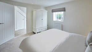 A bedroom with a large bed, a wardrobe, a radiator, and a window. - Host Stay The Hay Loft (Wakefield)