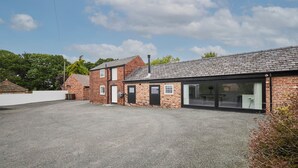 A two-story brick building with a gravel driveway and a large glass door entrance. - Host Stay The Hay Loft (Wakefield)