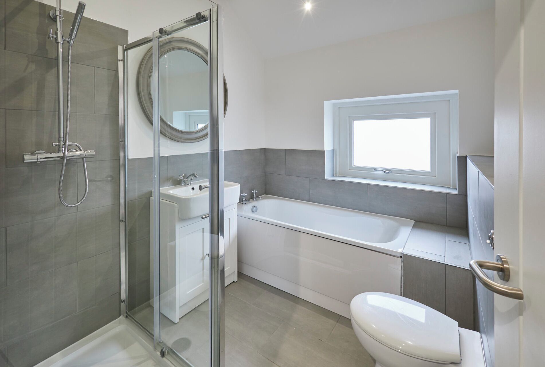 Un bagno moderno con doccia vetro, lavabo sospeso, vasca da bagno e toilette.
