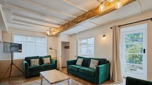A spacious living room with two green sofas, a wooden coffee table, and a floor lamp. - Host Stay Cragg Cottage (Whitby)