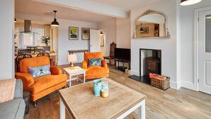 Ein Wohnzimmer mit zwei orangenen Sofas, einem Holztisch und einem Kamin.