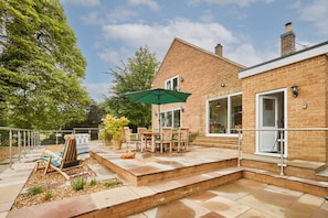 A patio with outdoor furniture, a table, and a green umbrella. - Host Stay The View at Orchard View (Ashbourne)