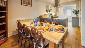 Ein Essbereich mit einem Holztisch, gedeckt für ein Frühstück, einschließlich Croissants, Obst und Getränken.