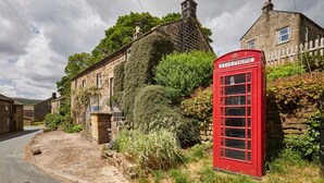 A traditional stone building with a red telephone booth in front. - Host Stay Clackgill Cottage (Harrogate)