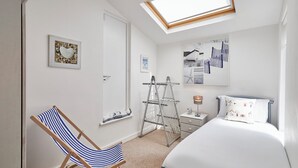 A bedroom with a bed, a chair, a drying rack, a nightstand, and a skylight. - Host Stay The Hideaway (Scarborough)