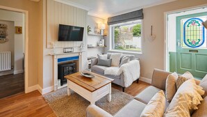 Ein Wohnzimmer mit Kamin, Fernseher, einer Couch und einer grünen Tür.