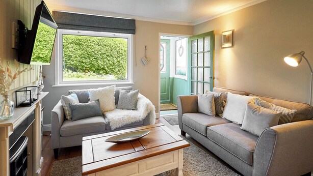 Ein gemütliches Wohnzimmer mit zwei Sofas, einem Couchtisch und einem an der Wand befestigten Fernseher.