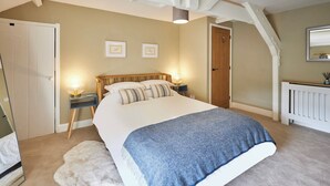 Une chambre à coucher avec un grand lit, deux tables de chevet avec des lampes, une porte en bois et un radiateur.