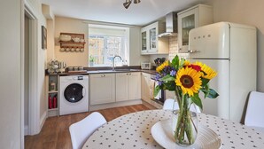 Une cuisine moderne équipée d’un lave-linge intégré, d’un réfrigérateur et d’un coin repas avec une table dressée pour deux personnes.