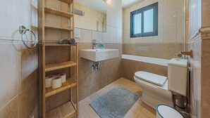 Un baño moderno con estante de madera, inodoro, lavabo y ducha.